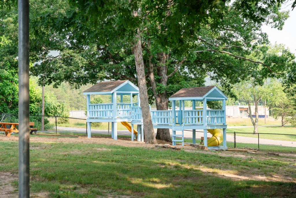 Blue wooden playground with two roof sections and a yellow slide